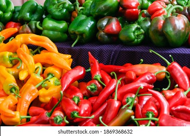 Table piled with red, yellow, and green chili and bell peppers