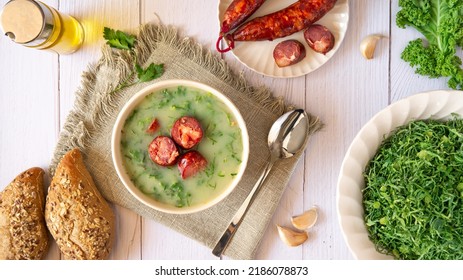 Table With Portuguese-style Soup Called Caldo Verde And Bread, Cabbage Julienne, Oil, And Chorizo Sausage. Flat Lay