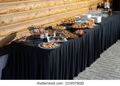 The Table Is Reserved For Catering, A Beautiful Black Tablecloth With A Wooden Wall In The Background.