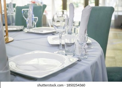 The table in the restaurant is served for lunch. On a table with a white tablecloth, empty wine glasses, a plate, napkins. Selective focus