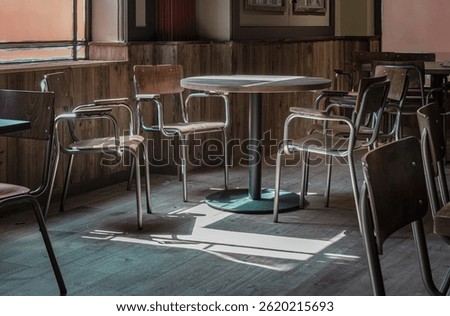 Table at a restaurant with sunlight coming in through the Large windows, casting beautiful light and shadow patterns on the dining table and chairs at empty restaurant. use it as your Wallpaper,Poster