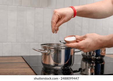 Table salt added to pot, salt boiling food close up