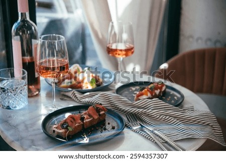 A table served for a dinner with different kinds of appetizers and rose wine in a bar or restaurant.