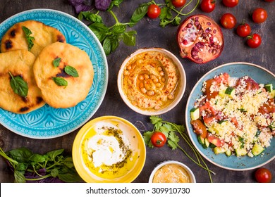 Table Served With Middle Eastern Traditional Vegetarian Dishes. Hummus, Tahini, Pitta, Couscous Salad And Buttermilk Dip With Olive Oil. Dinner Party