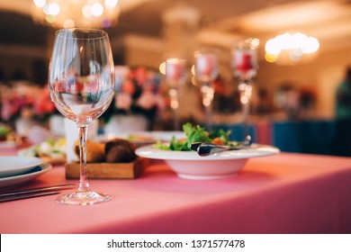 Table Served For Special Occasion. Empty Plate, Glasses, Forks, Napkin And Flowers On Table Covered With White Tableclothes. Elegant Dinner Table. White Table Setting