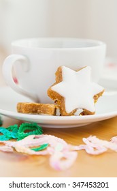 Table served to tea drinking. White cup of tea, star cake and Christmas decoration on the wooden table.