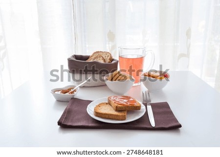 Table set for breakfast with bisquits with jam, bread, cookies, cup of tea