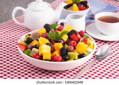 A Table Set for Breakfast with Fresh Fruit Salad on a Red Plaid Table Cloth