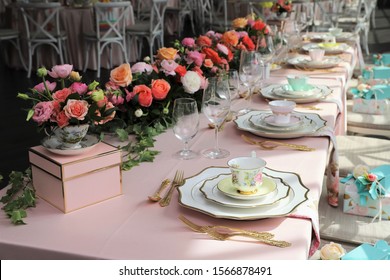 Table set up for bridal shower on bright spring day with flowers and vintage tea cups on each plate