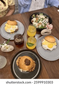 A table set with a delicious breakfast spread including eggs, bagels, salad, pastries, and fresh juice.