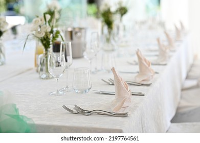 Table Set For Dinner With Flower Composition In Restaurant, Luxury Interior Background. Wedding Elegant Banquet Decoration And Items For Food Arranged By Catering Service On White Table