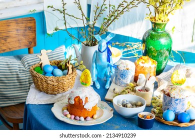 table set for Easter on veranda on sunny spring day decorated with flowers and Easter decor, eggs, cake and willow branches, Easter family celebration