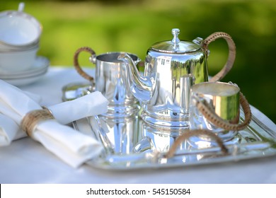 Table Set For An English High Tea, Or Afternoon Tea, Outside With Silver Teapot And Linen Tablecloth