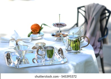 Table Set For An English High Tea, Or Afternoon Tea, Outside With Silver Teapot And Linen Tablecloth