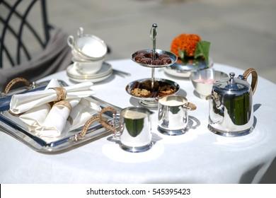 Table Set For An English High Tea, Or Afternoon Tea, Outside With Silver Teapot And Linen Tablecloth