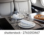 A table set for in-flight dining inside a modern executive business jet, highlighting a luxurious private aviation cabin interior.