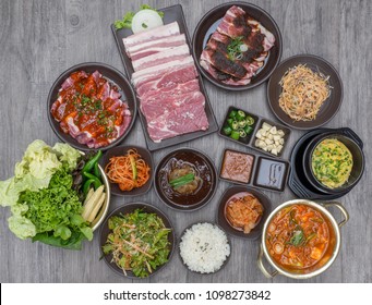 Table of set of korean barbecue, pork, meat, rice, vegetables, sauce and hood, ready for grill