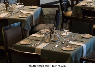 Table Set And Laid For Four People In A Restaurant Or Hotel Dining Room With Ambient Or Low Lighting