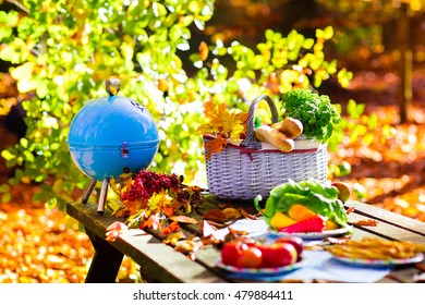 Table Set For Lunch Outdoors In Beautiful Sunny Autumn Park. Charcoal Grill And Picnic Basket With Baguette Bread, Sandwich, Fruit And Vegetables. Cooking For Bbq And Grill Party In Fall.