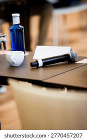 Table set with a microphone, blue bottle, coffee cup, and name card for a business conference