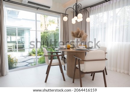 Table set on round table in modern style dining room interior of modern home. Dinning room with grass flower and big window.