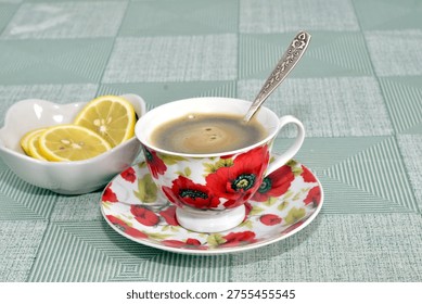 The table is set for tea. There is a cup of tea and a vase with sliced ​​lemon on the table.