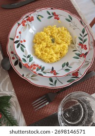 Table setting with bright tableware, berries, and twigs. Saffron risotto on plate. Traditional Italian food. Aesthetics and lifestyle. Interior design. 