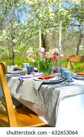 Table Setting And Cage With Flowers In Garden