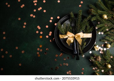 Table setting for celebration Christmas and New Year Holidays on  table. Festive place setting for christmas dinner with black plate and natural decorations. Top view. Copy space.