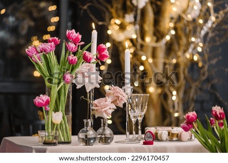 Table setting for couple on Valentine's day in restaurant. Luxury romantic date. Dinner setup. Engagement, ring in red box. Location for surprise marriage proposal. Decoration flowers, decor candles.