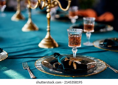 table setting decorated tableware with gold rim candlesticks floristry cutlery with patterns faceted embossed glasses blue velvet tablecloth napkins - Powered by Shutterstock