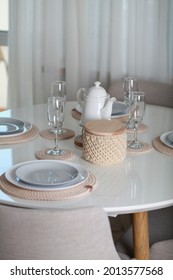 Table Setting With Dishes And Tableware In Stylish Modern Interior. No People. Dining  Table With Place Settings. Plates On Knitted Napkins, Glasses And Closed Crochet Basket For Nuts Or Fruits.