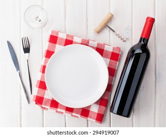 Table Setting With Empty Plate, Wine Glass And Red Wine Bottle. Top View Over Rustic Wooden Table Background