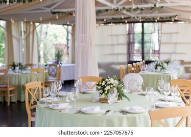 Table setting and flower composition with green and white flowers on a party table indoors. Restaurant with beautiful decoration, wedding party decor concept - Powered by Shutterstock