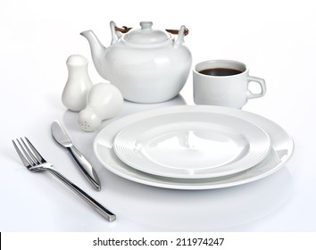 Table setting with fork, knife, plates, cup of coffee and coffee pot.  Isolated on white background