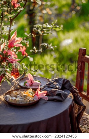 Table setting in garden on sunset light. Table decorated with magnolia flowers under magnolia tree
