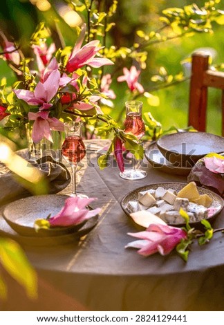 Table setting in garden on sunset light. Table decorated with magnolia flowers under magnolia tree