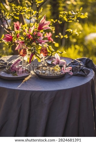Table setting in garden on sunset light. Table decorated with magnolia flowers under magnolia tree