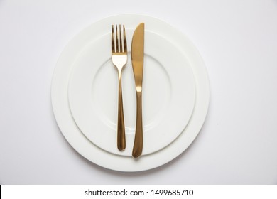 Table Setting Gold And White, Formal Dinner. Golden Fork And Knife On White Set Of Dishes Isolated, White Background, Top View