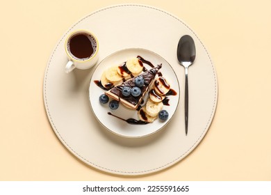 Table setting with piece of birds milk cake, blueberries, chocolate topping, banana slices, cup of coffee and spoon on beige background - Powered by Shutterstock