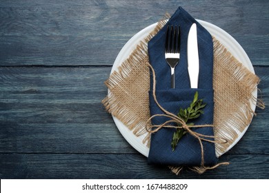 Table setting. plate and cutlery in a blue napkin, fork and knife on a blue wooden table. top view - Powered by Shutterstock