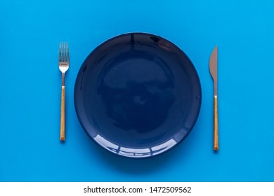 Table setting with plates and flatware on blue background top view