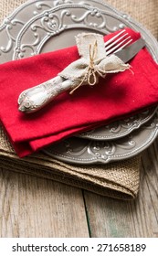 Table setting: plates, vintage fork, knife and spoon with napkin on rustic wooden table. Top view point.