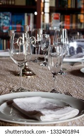 Table setting: plates, wine glasses, spoon, candle.