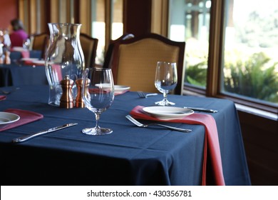 Table setting in  a restaurant with a blue tablecloth, red napkins and white plates