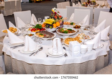 Table setting in a restaurant. Table decorated with flowers and beautiful appetizers salads on a white tablecloth. Holiday dinner. Almaty, Kazakhstan March 20, 2020