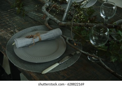 table setting in a rustic style. plants on the dining table. table made of dark wood. Cutlery on the table.