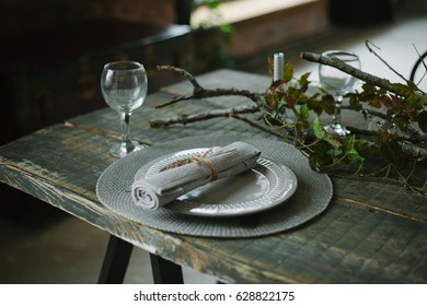 table setting in a rustic style. plants on the dining table. table made of dark wood. Cutlery on the table.