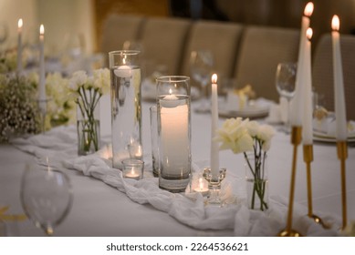 Table setting, serving closeup. Wedding setup detail. Banquet decoration in hall restaurant. Luxury reception. Festive table covered tablecloth, decorated composition flowers and candles in party area