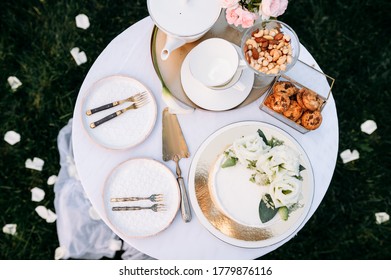 Table setting, teapot, teacups, cake, side view